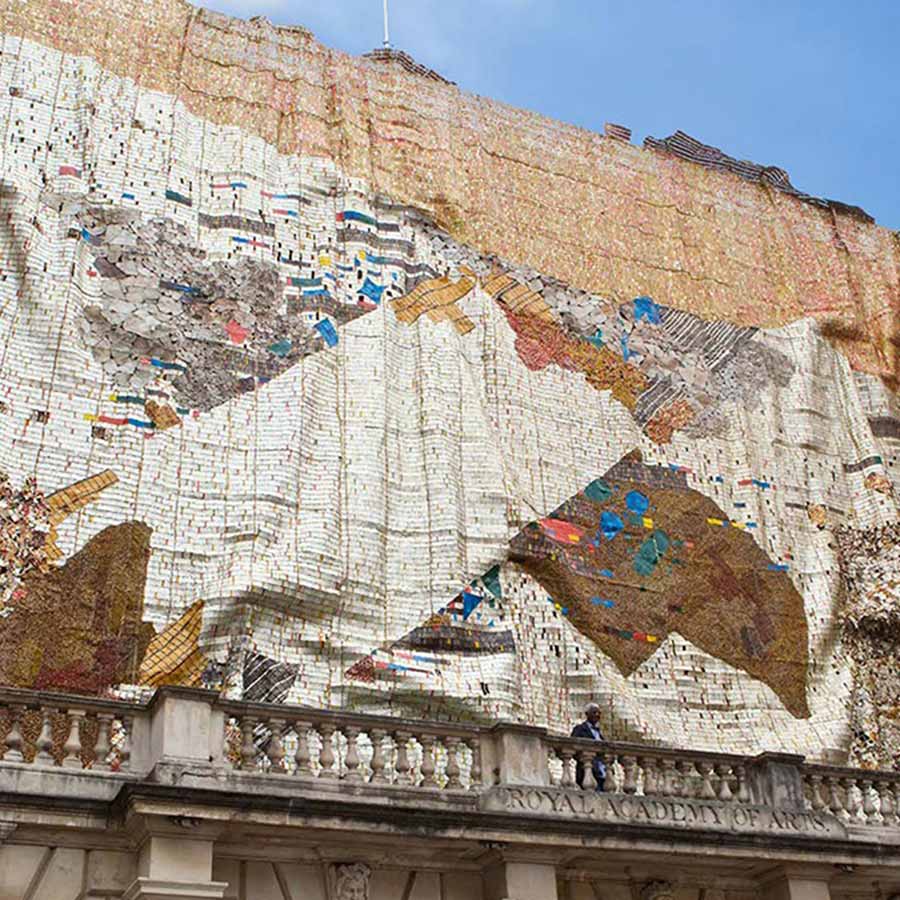 <strong>El Anatsui</strong> in front of <em>TSIATSIA - searching for connection</em>, 2013.
Aluminium (bottle-tops, printing plates, roofing
sheets) and copper wire, 15.6 x 25 m 
at the Royal Academy of Arts, 2013.